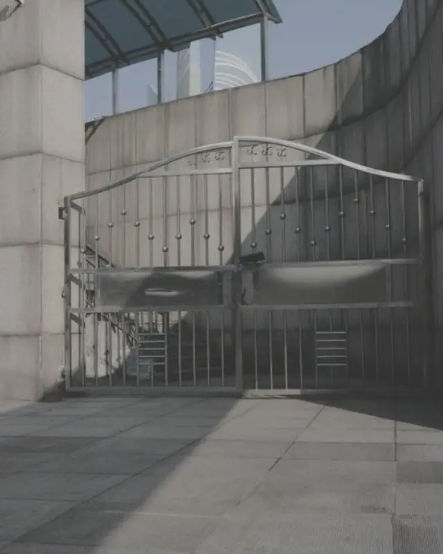 Stainless steel double swing gate with spear-top bars and a solid kick panel, set in a curved concrete wall
