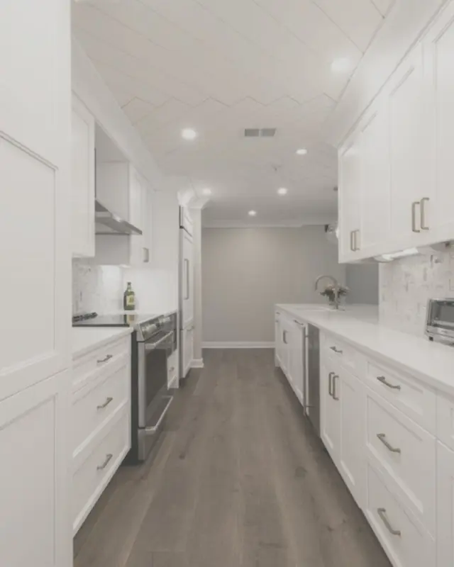 White galley kitchen with shaker doors floor to ceiling and a stone top along one wall