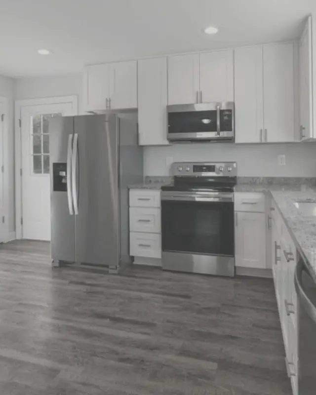 L-shaped white kitchen with shaker doors and a granite top