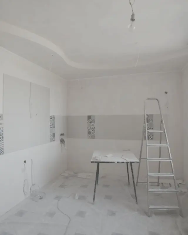 Kitchen under renovation with a new plaster ceiling and splashback tiles going on before the cabinets